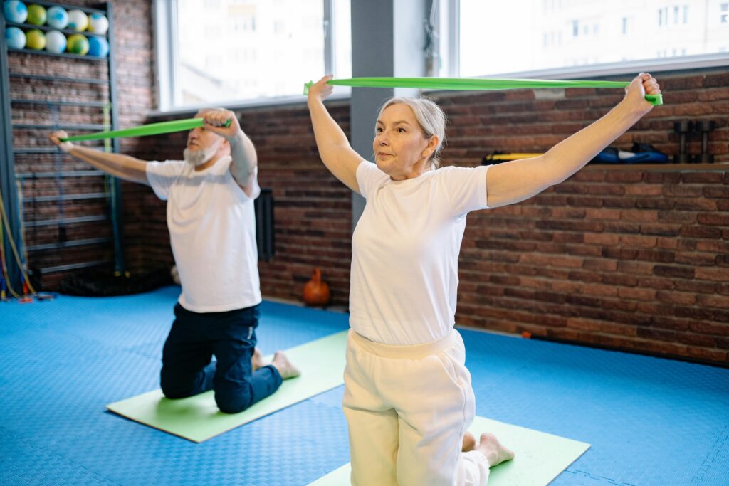 senior couple in white exercising with resistance bands