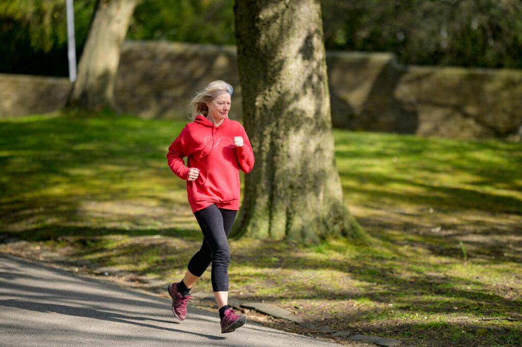 senior woman running in a red sweatshirt and black pants